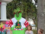 A candid photo of the Grinch as he stands with his hands on his hips, as a boy and a girl look approach for a photo op.