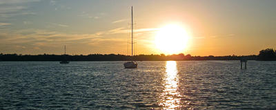 sailboats on local waters with sun setting in background 