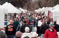 Rows of white tents form alleyways filled with event-goers.